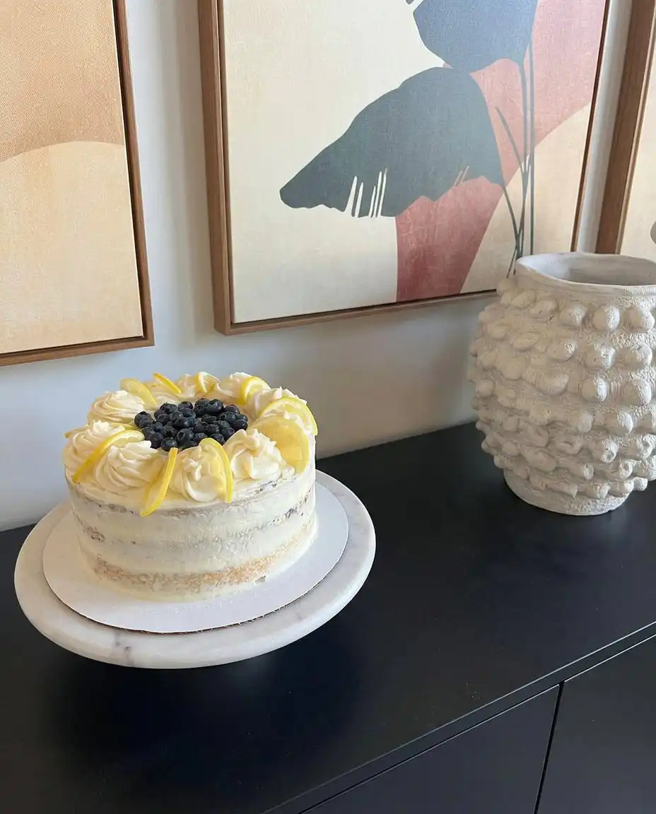 A slice of lemon blueberry cake on a white china plate with gold trim