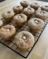 A tray of freshly baked carrot cake zucchini muffins cooling on a wire rack