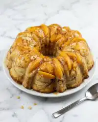 A golden Cream Cheese Peach Cobbler Pound Cake on a white porcelain platter.