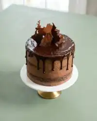 Three layers of Classic Chocolate Zucchini Cake cooling on a wire rack in a rustic kitchen.