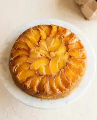 A golden brown Easy Peach Pie Filling Dump Cake resting in a clear glass baking dish.
