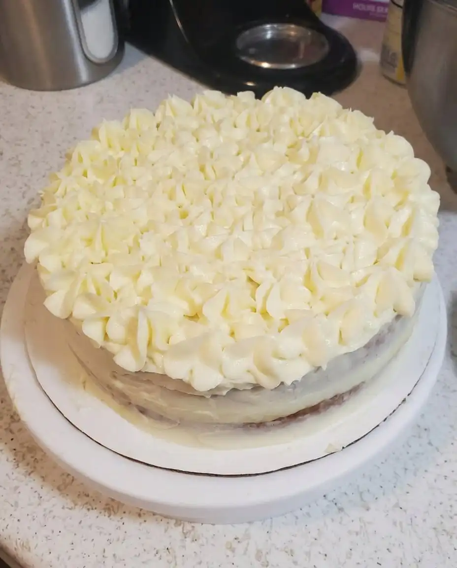 A single slice of lemon cake on a white porcelain plate with a garnish of mint and a lemon twist