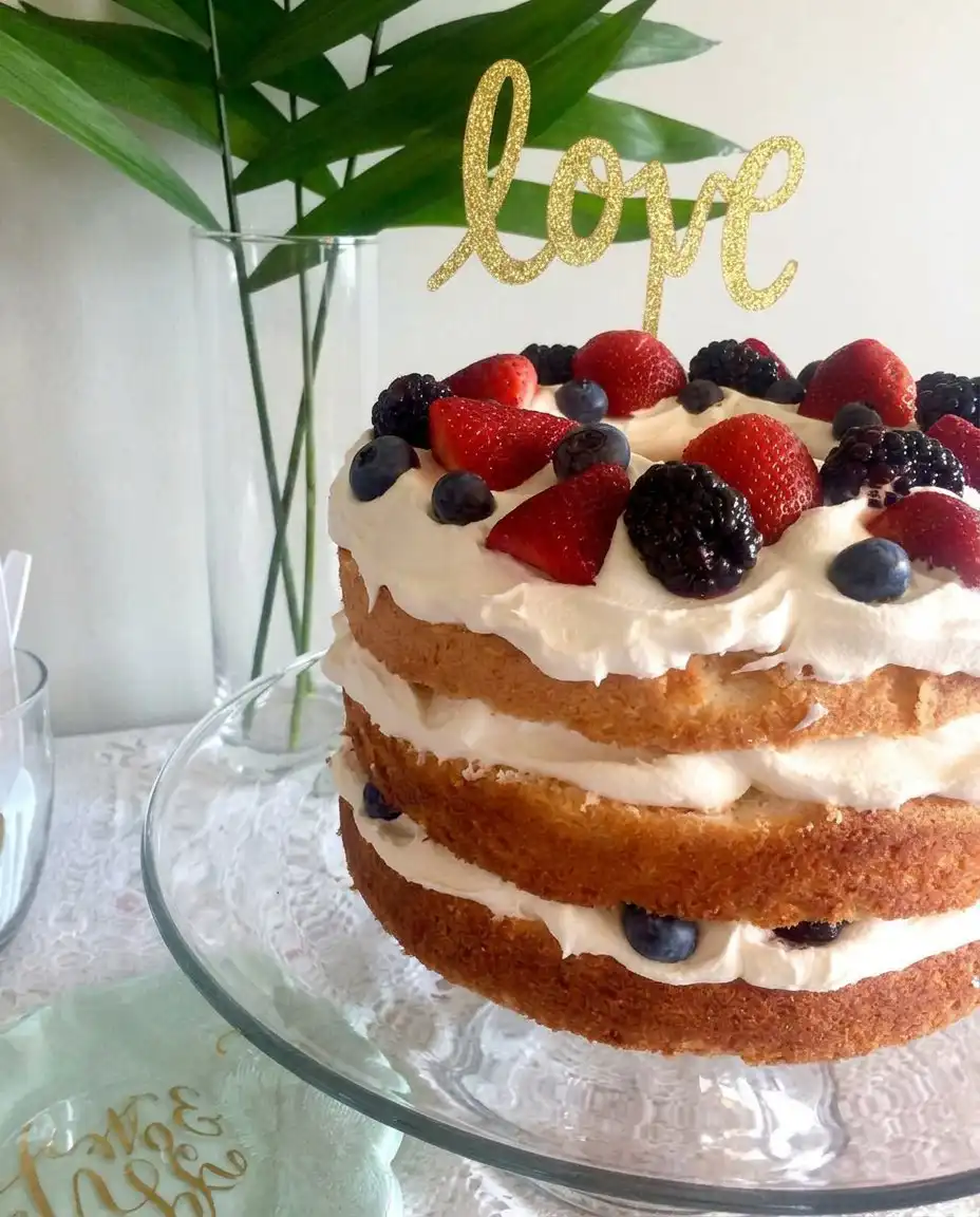 A single, clean slice of layered angel food cake with berries on a delicate white dessert plate, garnished with a sprig of fresh mint.