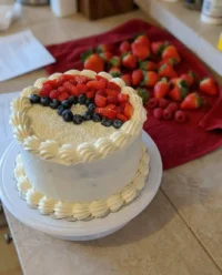 A clean slice of summer berry poke cake showing red and blue fruit sauce filled into a tender white crumb.