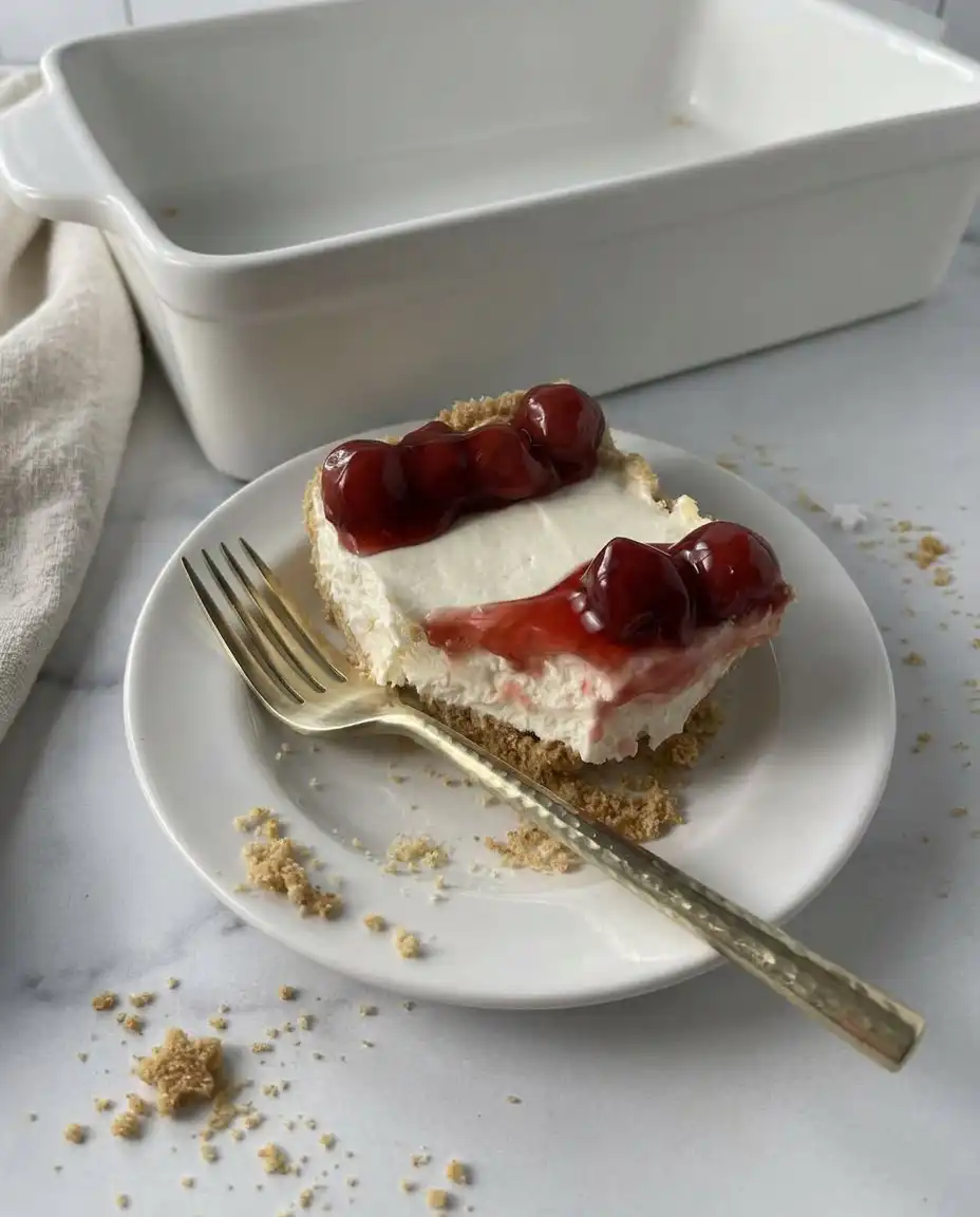 A spatula gently folding stiff whipped cream into a smooth cream cheese base.