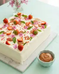 A close up of the Best Strawberry Sheet Cake cooling in its pan with a golden crumb.