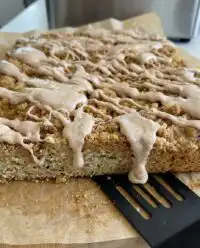 A thick slice of zucchini crumb cake with heavy cinnamon streusel and white glaze
