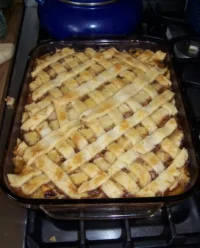 A close up view of a golden brown peach cobbler in a white ceramic dish
