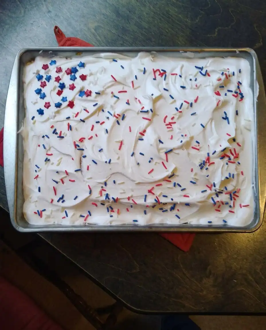 The finished Red White and Blue Patriotic Poke Cake decorated with swirls and sprinkles