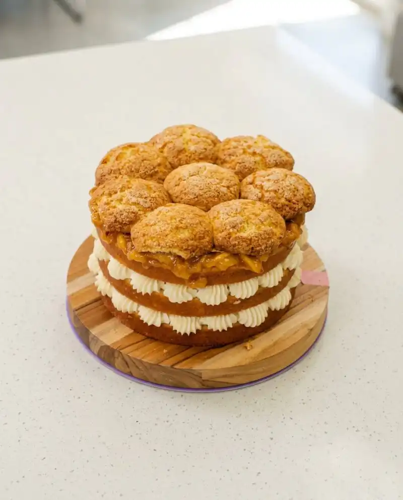 A thick slice of Peach Cobbler Layer Cake showing the cornmeal crumb and roasted fruit layers.