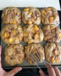 A tray of golden brown peach cobbler muffins with thick streusel topping