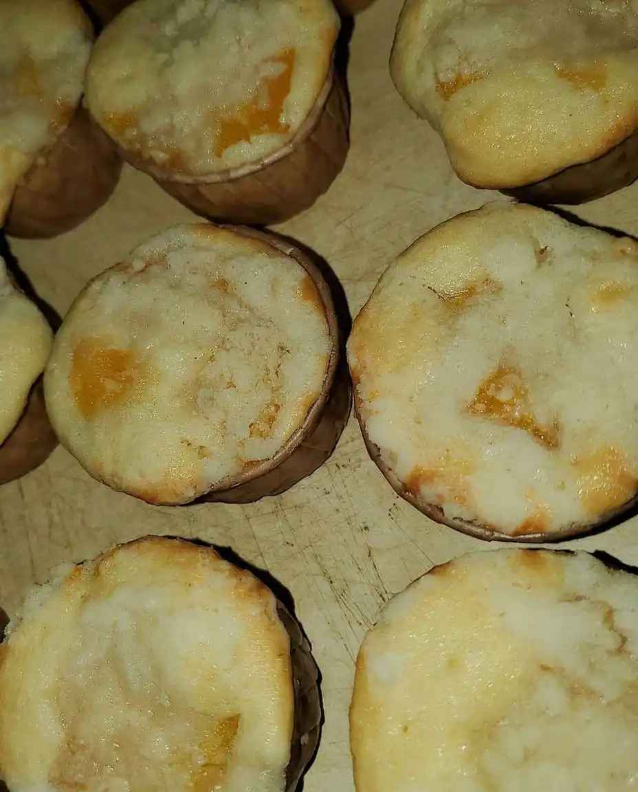 A peach cobbler muffin on a plate next to a cup of coffee
