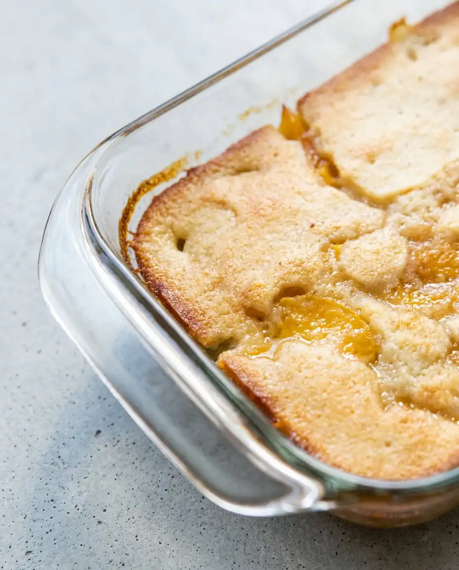 A bowl of Peach Cobbler with Canned Peaches served on an antique floral plate.