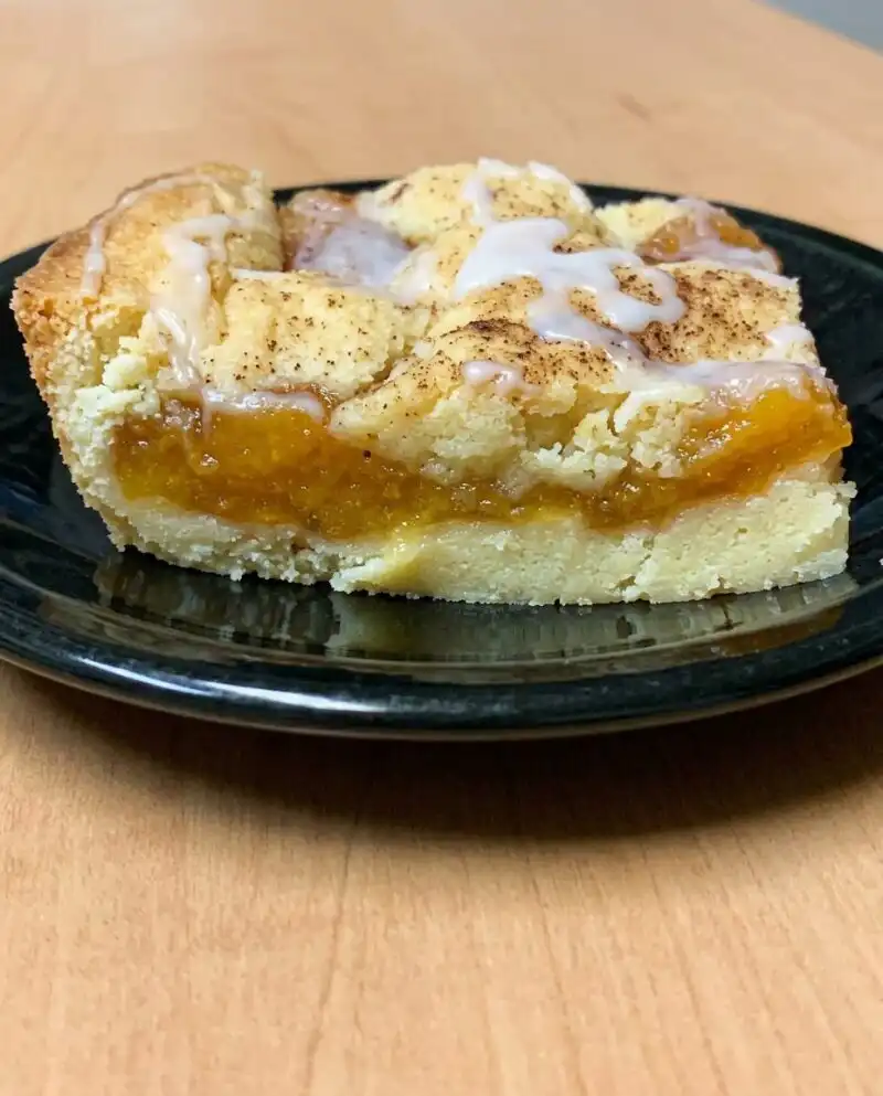 Home - Cake Half - Small Batch Baking & Cupcakes 4 A freshly baked Peach Coffee Cake sitting on a rustic wooden table in a sunlit kitchen.
