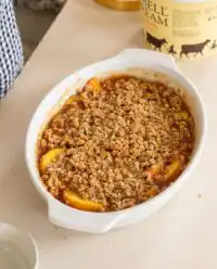 A warm Peach Crisp rests on a wooden counter in a heritage kitchen setting.