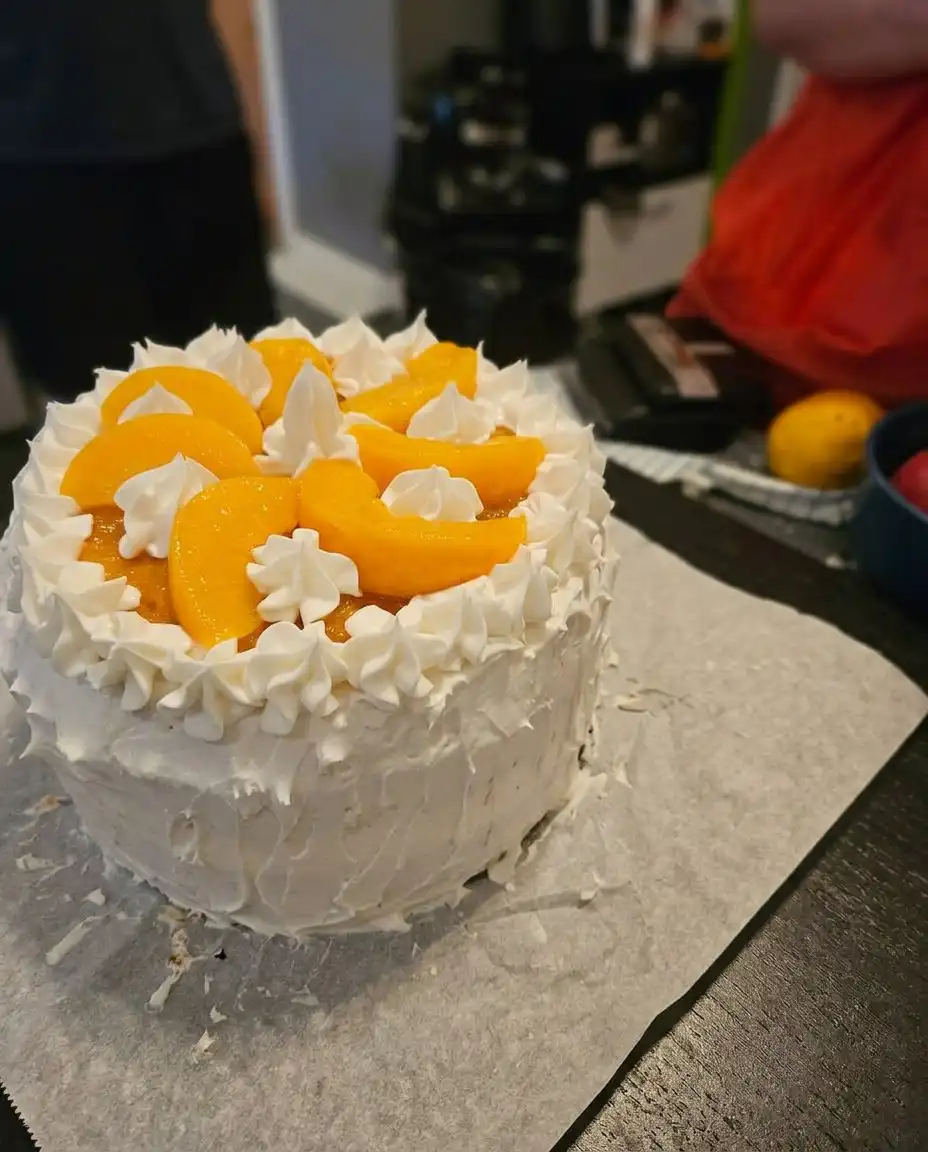 A single slice of Peaches and Cream Layer Cake on a white plate with a gold fork.