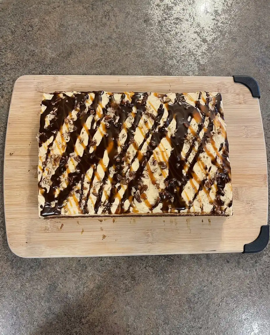 A single slice of chocolate turtle cake on a white plate with caramel drizzle