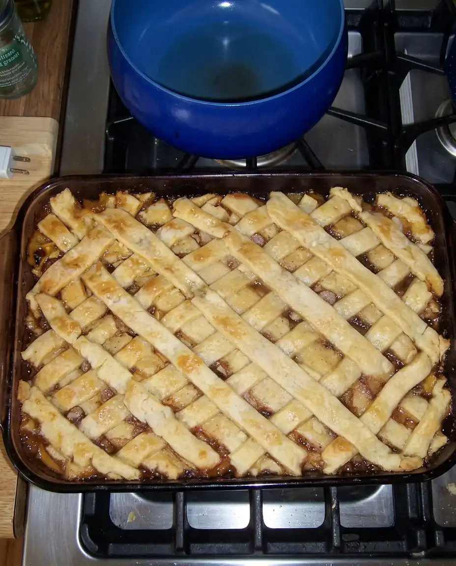 A generous serving of peach cobbler on a white plate with a melting scoop of vanilla ice cream