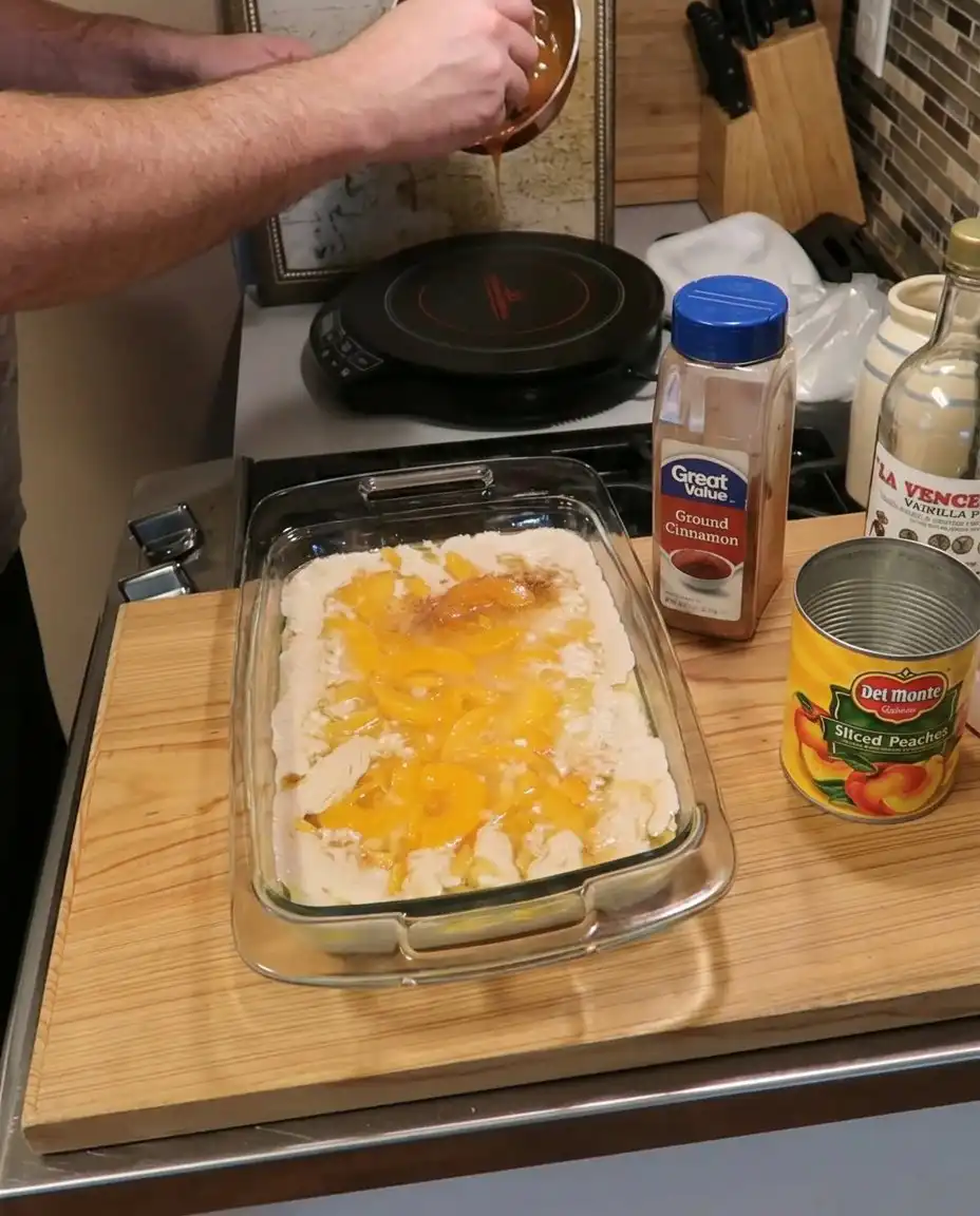 A wooden spoon scooping out a portion of warm peach cobbler
