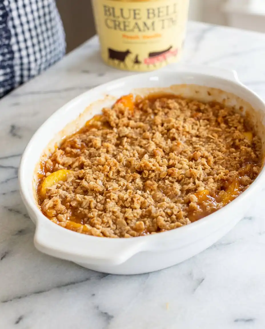 A bowl of Peach Crisp served with a drizzle of fresh heavy cream.