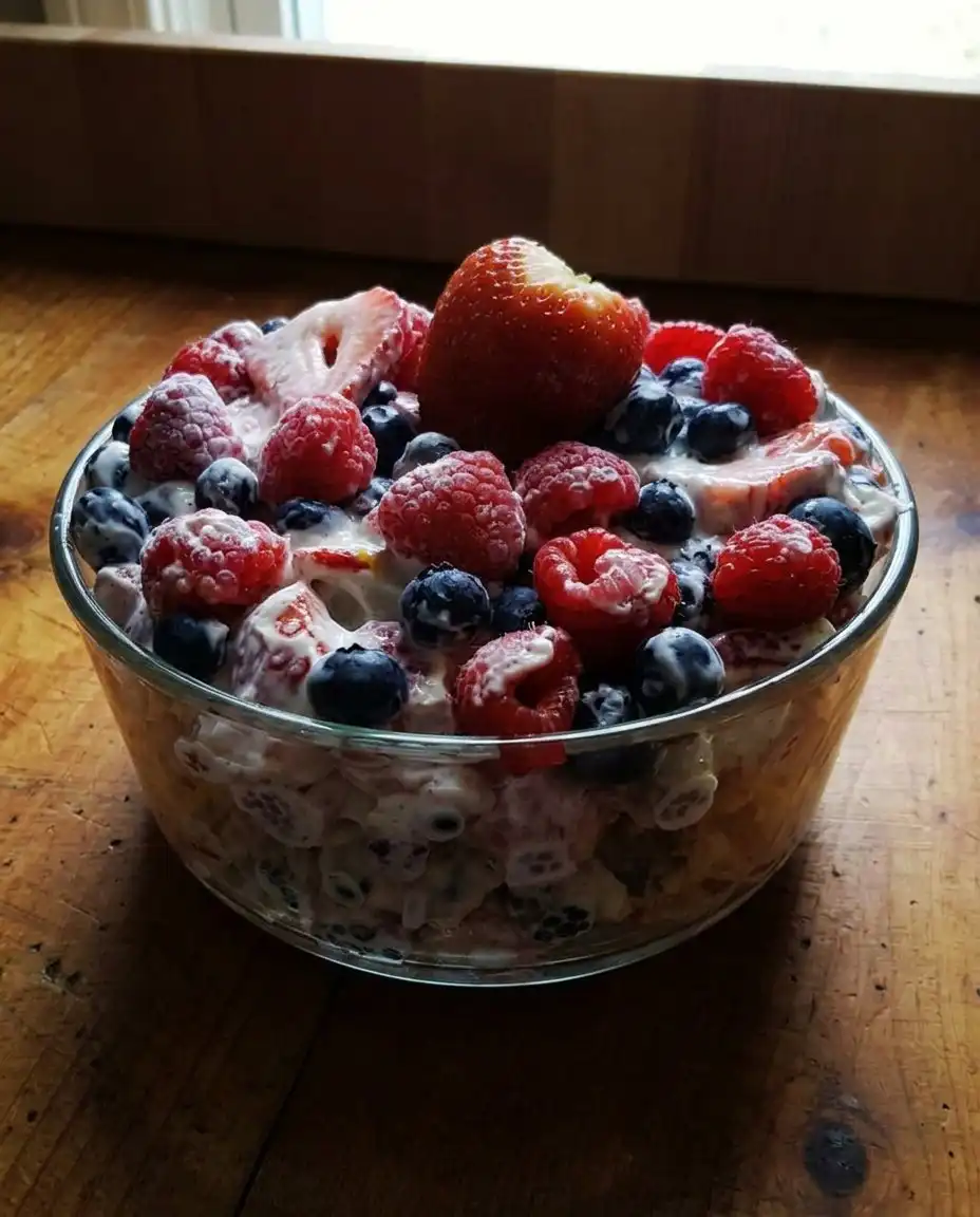 A spoonful of creamy berry cheesecake salad being served onto a vintage floral plate.