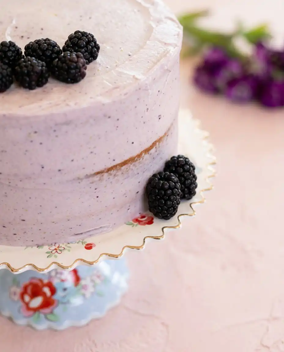A clean slice of Blackberry Lemon Cake showing the yellow layers and purple fruit filling.