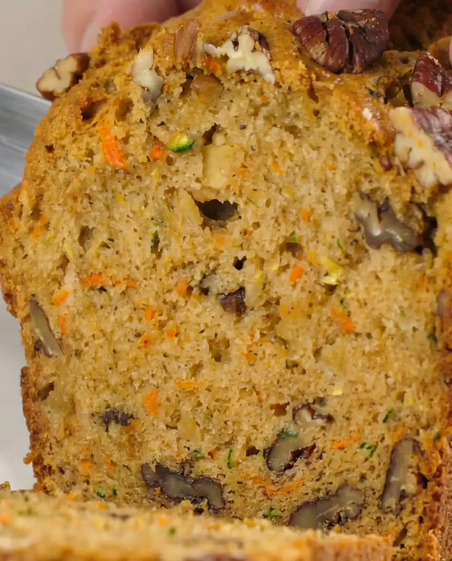 Slices of carrot apple zucchini bread served on a white plate with butter