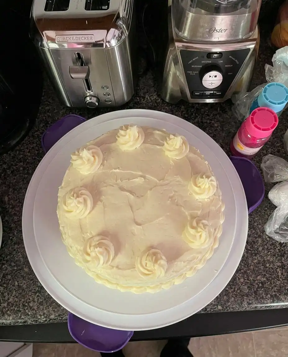 A whole lemon velvet cake with one slice removed, sitting next to a cup of tea.
