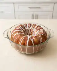 A golden Southern Peach Cake sitting on a floral vintage ceramic plate in a sunlit kitchen.
