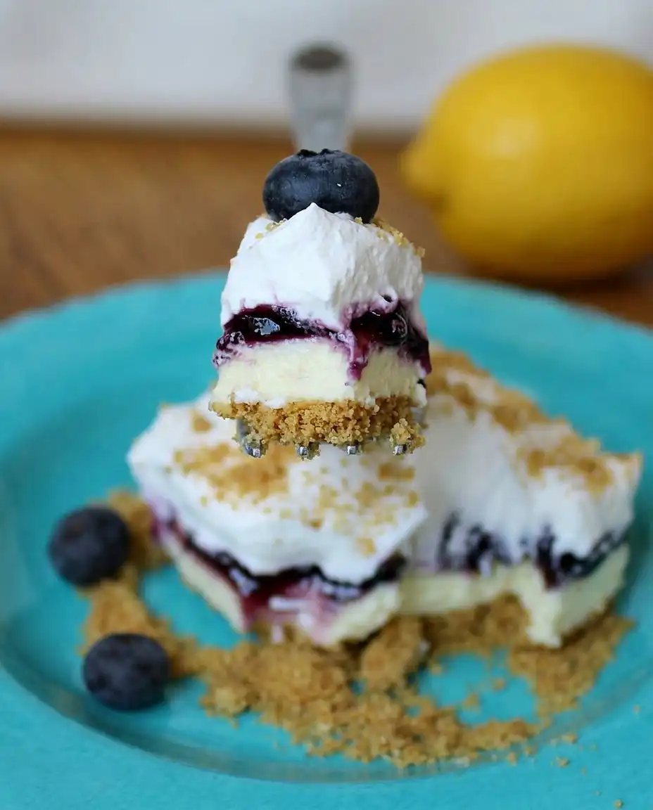 Spreading the lemon pudding layer onto a graham cracker crust in a 13x9 dish.