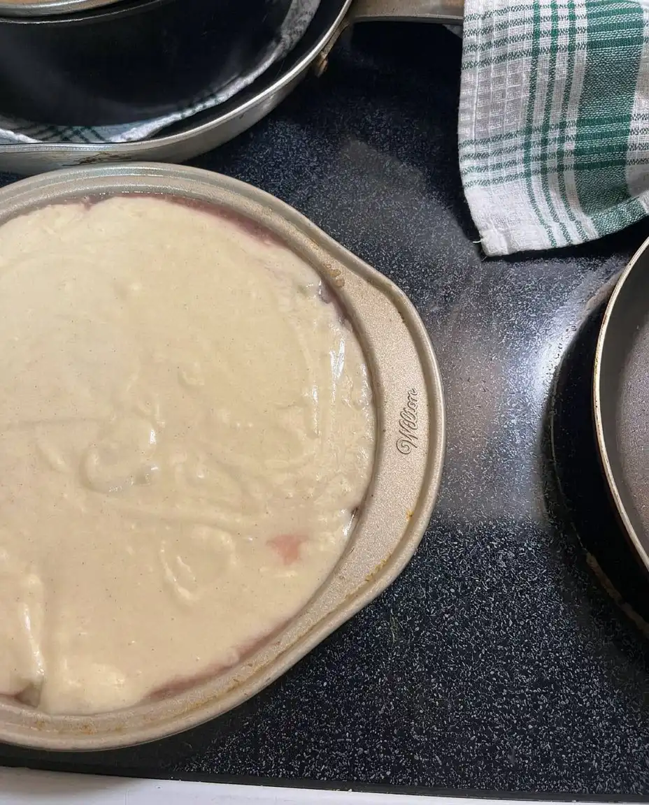 A person squeezing juice out of crushed pineapple through a sieve