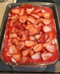 A close up shot of Strawberry Heaven showing layers of angel food cake, cream cheese filling, and bright red strawberry glaze.