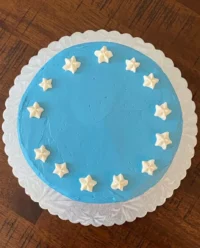 A Red White and Blue Fourth of July Poke Cake decorated like an American flag on a wooden picnic table.