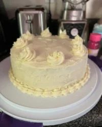 A beautiful slice of Lemon Velvet Cake with cream cheese frosting on a vintage floral plate.