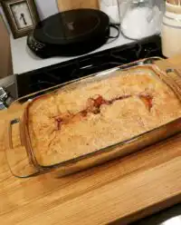A golden brown super easy peach cobbler in a glass baking dish