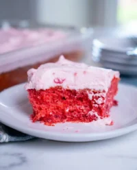 A 9x13 Raspberry Fluff Cake topped with whipped cream and fresh berries on a rustic wooden table