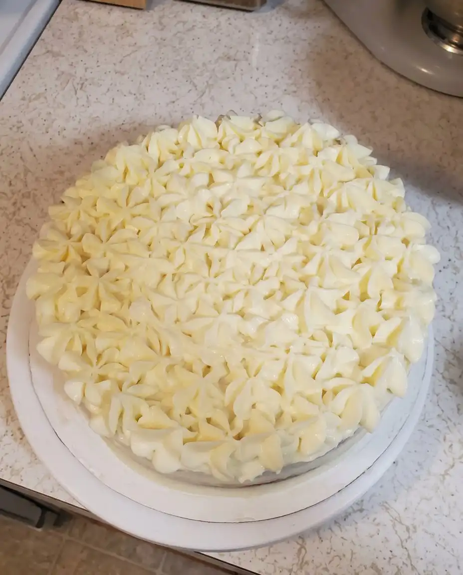 A silver whisk lifting egg whites out of a bowl to show soft glossy peaks