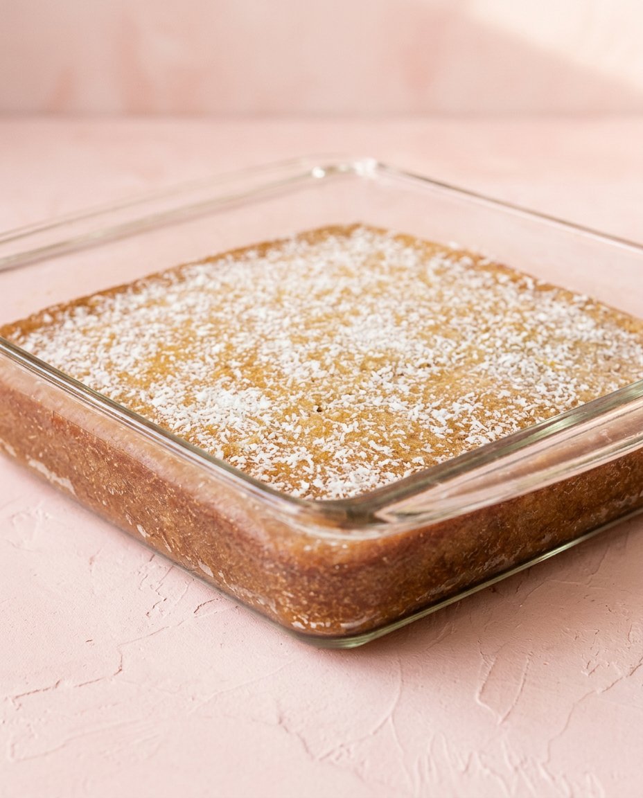 A single slice of Zucchini cake with lemon glaze on a white plate.