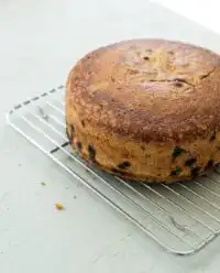 A rustic Blueberry Lemon Olive Oil Cake cooling on a kitchen table with flour in the air