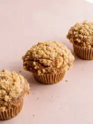Freshly baked Carrot Cake Muffins with Streusel Topping sitting on a dark metal cooling wire rack.