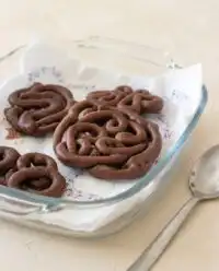 A warm chocolate funnel cake lightly dusted with white powdered sugar on beautiful vintage china.
