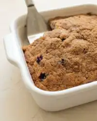 A golden slice of Classic Blueberry Coffee Cake showing rich layers of cinnamon streusel and dark jammy berries.