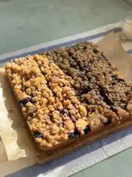 A freshly baked Classic Blueberry Coffee Crumb Cake in a square baking pan with a thick golden crumb topping.
