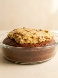 A Classic German Chocolate Cake with Coconut Pecan Frosting cooling on a vintage wire rack.
