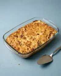A warm slice of Classic Pumpkin Dump Cake topped with toasted pecans and fresh vanilla ice cream.