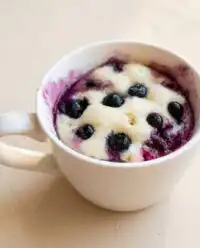A freshly baked Easy Blueberry Mug Cake served warm in a white ceramic mug.