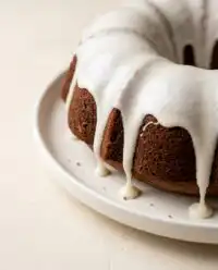 An elegant Pumpkin Spice Bundt Cake with a white powdered sugar glaze cascading down its sides.