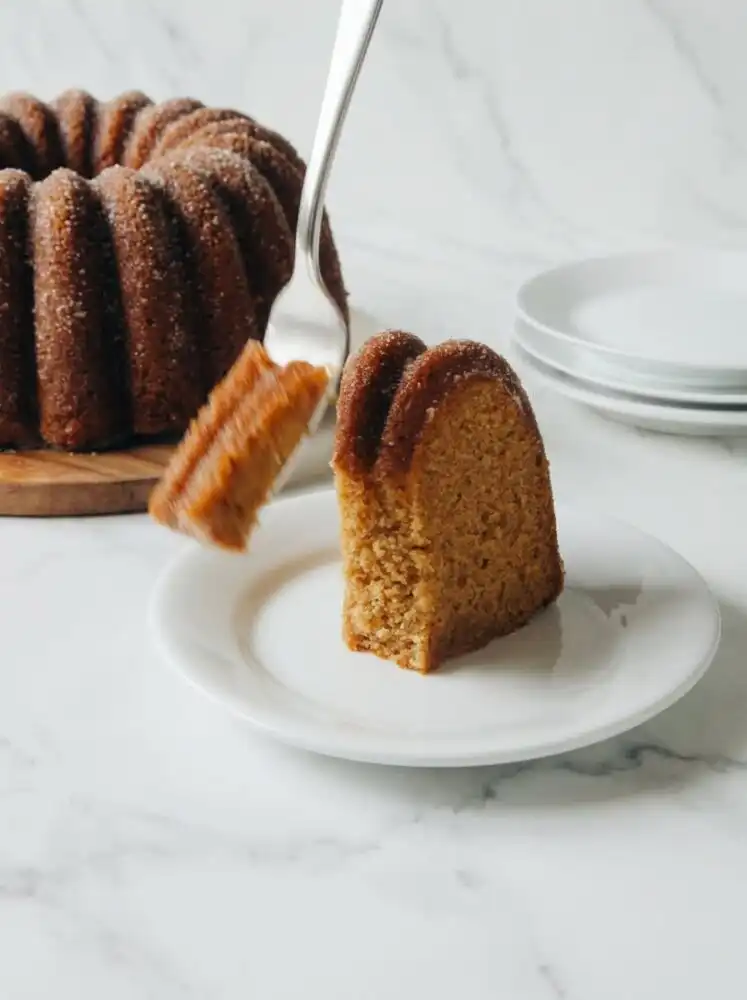 Home - Cake Half - Small Batch Baking & Cupcakes 1 A beautifully baked fluted Apple Cider Cake coated in cinnamon sugar, resting on an elegant white pedestal.