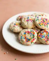 Freshly baked Funfetti Cake Mix Cookies with white chocolate chips in a vintage glass bowl.