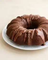 A freshly baked healthy chocolate zucchini cake cooling on a wire rack in a rustic kitchen.